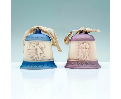 2 matte porcelain Christmas bells, one in a blue coloration and one in a purple coloration with an engraved scene each at the