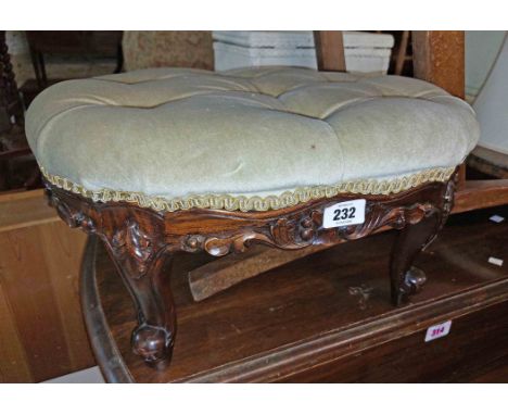 A Victorian mahogany framed footstool with button back velour upholstered oval top, set on short cabriole legs