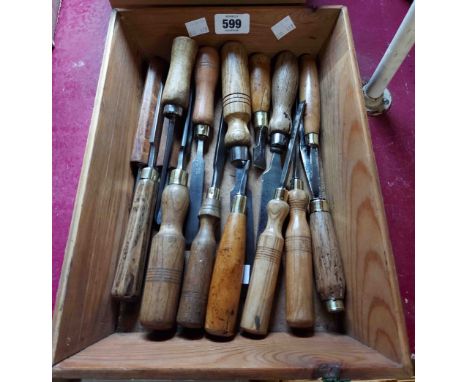 A wooden tray containing a quantity of vintage chisels