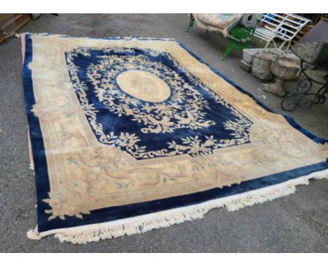 A Chinese washed wool carpet with central medallion and floral scroll motifs within a wide border on blue ground - 3.9m X 2.7