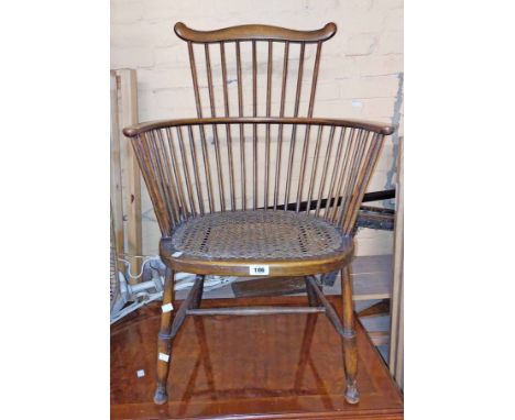 A vintage stained beech framed comb back bow elbow chair with rattan seat panel, set on simple turned supports