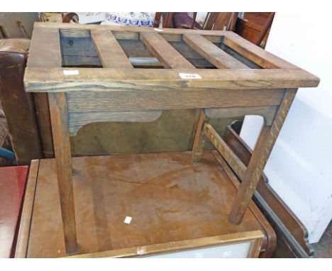 A vintage oak luggage stand with slatted top, set on bracketed supports