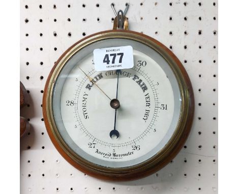 A vintage brass cased bulkhead barometer with printed dial and aneroid works, set on a mahogany wall plaque