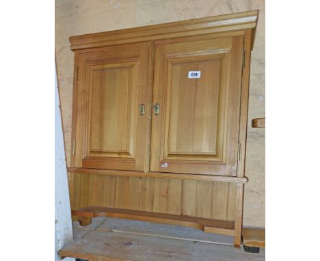 A 62cm modern pine wall hanging cupboard enclosed by a pair of panelled doors with open shelf under