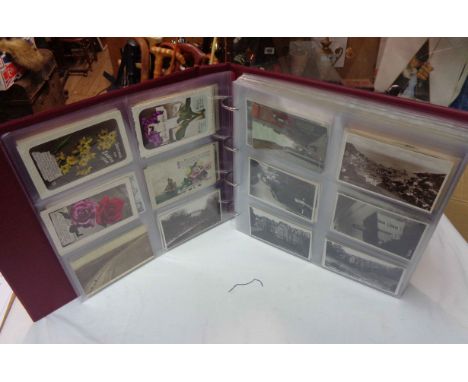 A box sleeved large red ring bound album containing a collection of plastic sleeve mounted early 20th Century and other postc