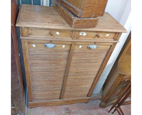 An 85cm vintage oak tambour fronted filing chest with two short drawers over two flights of internal slides, set on bun feet