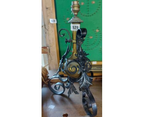 A brass lamp encompassed by a scrolled wrought iron stand