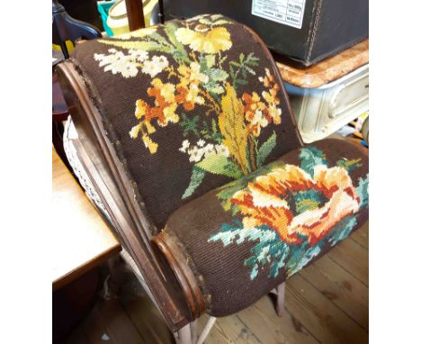 An early 20th Century walnut footstool with scroll top and floral woolwork tapestry, set on box frame base - wear