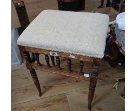 An Edwardian stained walnut piano stool with spindle set apron and upholstered seat, set on ring turned legs