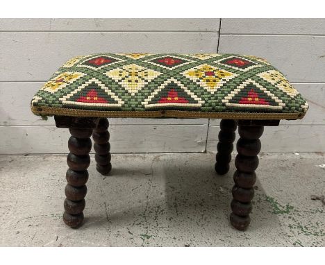 An arts and crafts stool on bobbin legs with an aztec style upholstered seat 