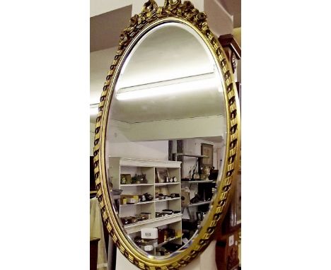 A gilt framed oval mirror with ribbon surmount 63 x 33cm
