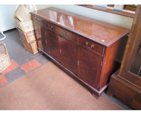 A reproduction crossbanded mahogany sideboard, with three frieze drawers over four doors on splayed bracket feet, 151cm wide