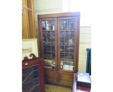 A 1930's oak display cabinet, with two lead glazed doors over two panelled doors on bracket feet, 98cm wide
