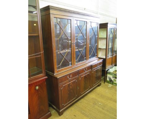 A reproduction mahogany bookcase, with dentil cornice over three astragal glazed doors, three frieze drawers and three panell