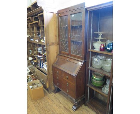 A 1920's oak bureau bookcase, with sunburst lead glazed doors, panelled fall, three long drawers and turned legs with bracket