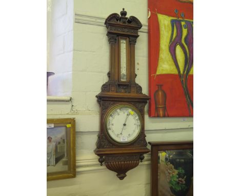 An Edwardian carved walnut Aneroid barometer retailed by Maple & Co. Ltd. London, the swan neck pediment over a mercury therm