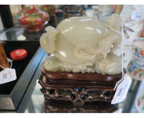 A Chinese green jade brush or ink pot, of egg form carved with a dragon and a peacock on a hardwood stand, 11cm wide