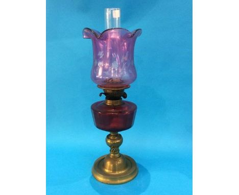 An oil lamp with Cranberry coloured reservoir and etched shade
