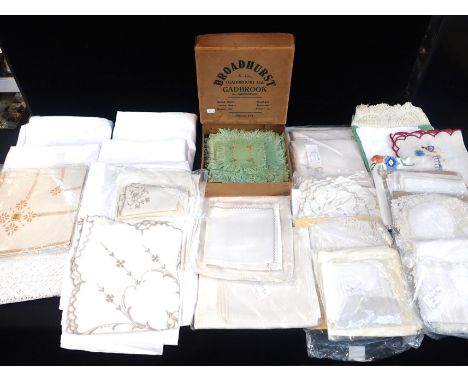 A COLLECTION OF VINTAGE LINENSincluding damask table cloths, and a set of embroidered mats contained in a vintage printed car