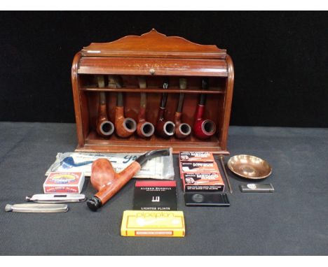 A MAHOGANY PIPE RACK WITH TAMBOUR FRONTwith a collection of vintage pipes and smoking accessories