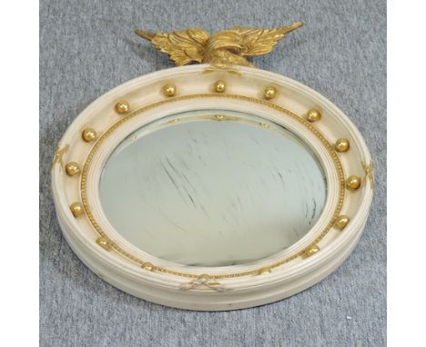 A cream painted and gesso convex wall mirror, surmounted by an eagle, 62 x 48cm overall