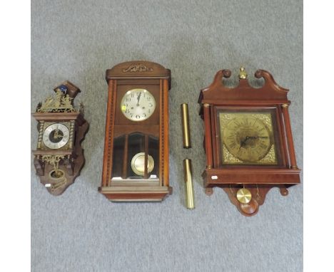 A reproduction wall clock with a brass dial, 74cm tall, together with two others smaller