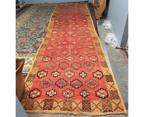 A runner with an orange ground and multiple geometric flower heads to a lighter border with geometric panels, 155 x 557cm