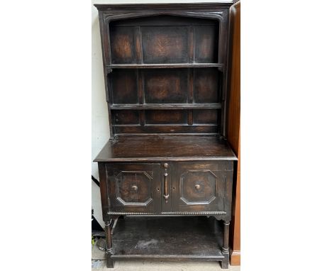 A 20th century oak dresser with a moulded cornice, two shelves and an enclosed back, the base with two cupboards on ring turn