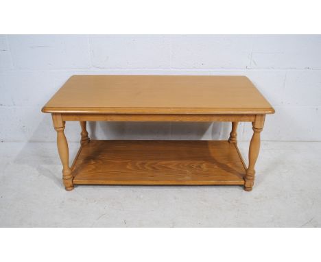 A light oak rectangular coffee table, raised on turned legs - length 100cm, depth 50cm, height 46cm