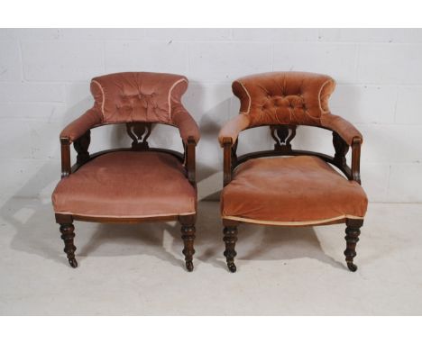 A pair of turn of the century upholstered tub chairs, with button back detailing and carved decoration, raised on turned legs