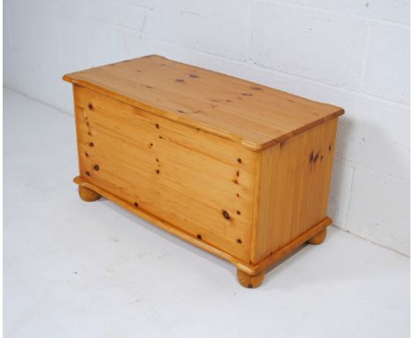 A modern pine trunk, raised on ball feet - length 82cm, depth 41cm, height 45cm