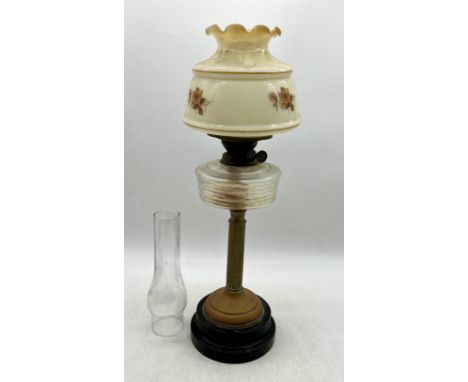 A brass columned oil lamp with floral decoration to glass shade with funnel. 