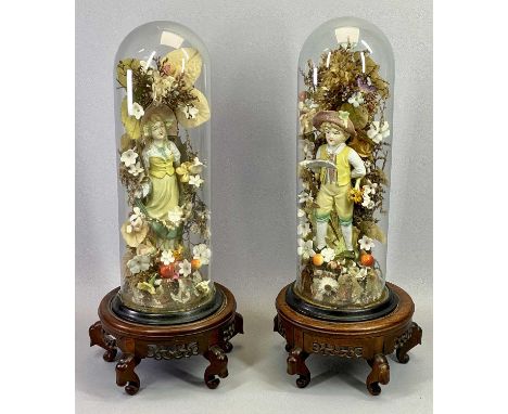 VICTORIAN GLASS DOMES, A PAIR - containing a pair of continental bisque figures of a boy and girl set amongst artificial and 
