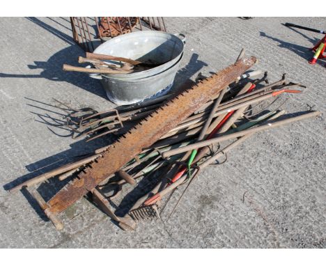 An assortment of tools and a galvanized bath. Including saws, rakes, pitchforks, etc. The bath L61cmAll items in this auction