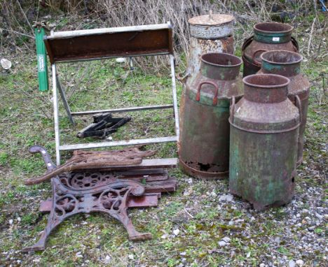 A group of metal milk churns.  A pair of metal bench ends with a chainsaw bench.