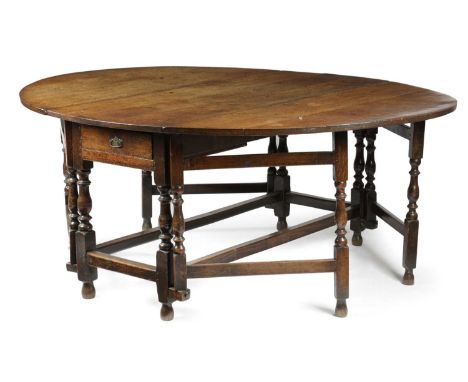 A LARGE QUEEN ANNE OAK GATELEG DINING TABLEEARLY 18TH CENTURYthe oval drop-leaf top above an end frieze drawer on turned balu