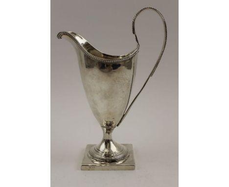 A George III silver helmet form cream jug, beaded rim and high hoop handle, on square platform base, London 1787, 118g