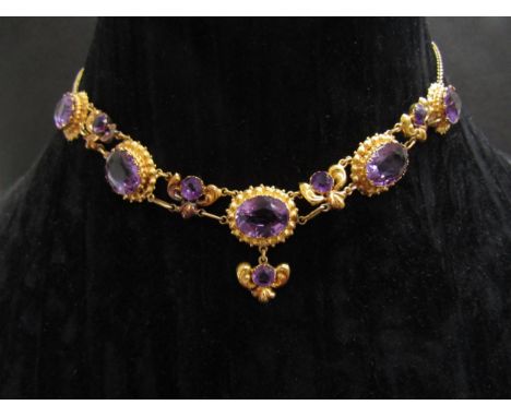 A 19th Century amethyst necklace, the graduated amethysts in ornate mounts, hung with a droplet (later chain, repaired), 39cm
