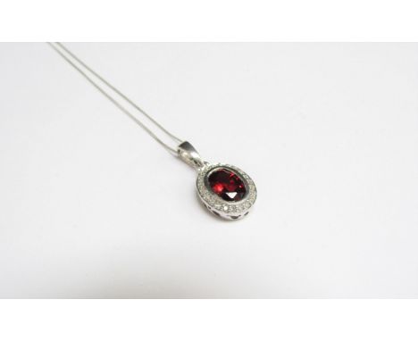 A 9ct white gold garnet and diamond oval pendant hung on chain stamped 375, 45cm long, 2.5g 