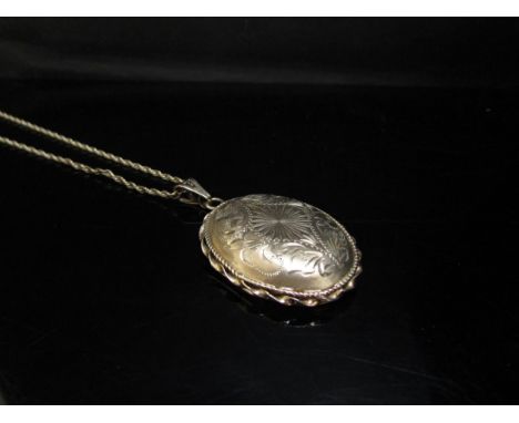 A 9ct gold engraved oval locket hung on a 9ct gold chain, 50cm long, 12.9g 