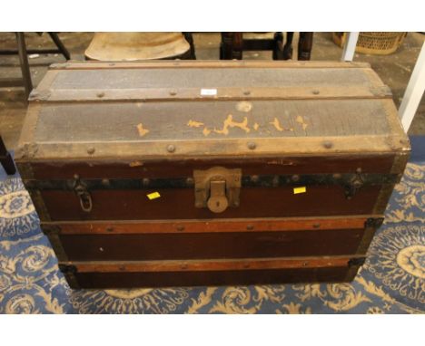 A dome topped trunk the interior lined with a blue stripped paper, height 56 cm, width 84 cm, depth 49 cm