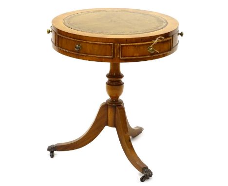 A yew drum shaped coffee table, the circular top with a brown leather inset, above an arrangement of three drawers and false 