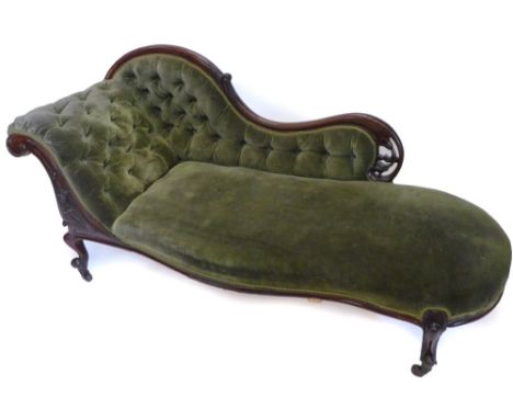 A Victorian mahogany showframe chaise longue, upholstered in buttoned green fabric, on scrolled carved cabriole legs with cer