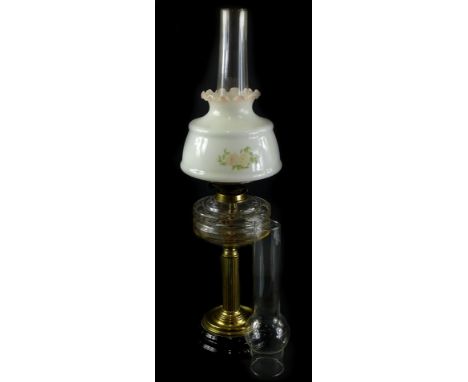 A Victorian brass oil lamp with clear reservoir, reeded column and ceramic base, later shade and two chimneys, 70cm H overall