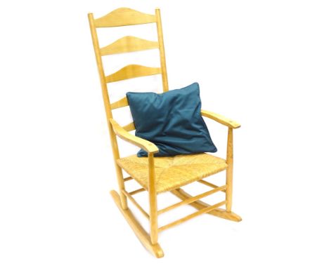 An ash ladder back rocking chair, of Clisset type, in the Manner Gimson, with a rush seat on turned supports.