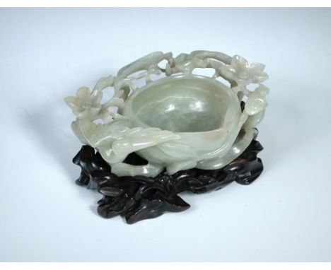 A grey green nephrite jade brush washer, the rim of the peach shaped bowl partially enclosed by blossoms and leaves with a cr