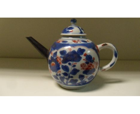 An 18th century Imari tea pot and cover, the bullet shape painted with floral reserves on an underglaze blue ground, the repl