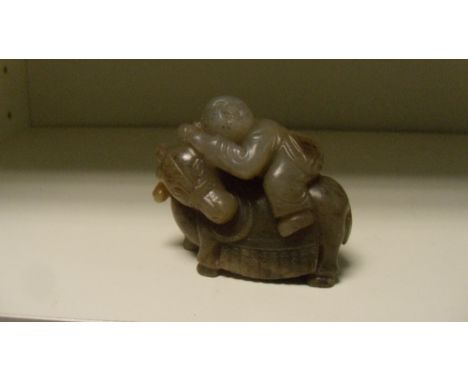 A dark grey jade water buffalo, its head turned back to support its boy rider, 6.5cm (2.5 in) wide  