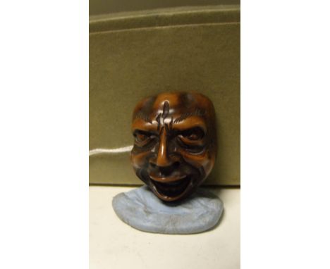 A wooden mask netsuke, possibly representing Shikami, the bald headed man laughing in a knowing way, 3.5cm (1.33 in) high  