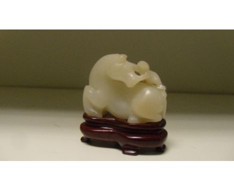 A mutton fat jade group of a reclining horse nuzzling the figure climbing onto its rump, 4.5cm (1.25 in) wide, with a wood st
